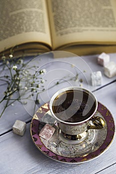 Cup of Turkish coffee with Turkish delights and heart shaped chocolate next to the old book