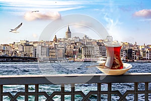 A cup of Turkish tea in a traditional glass against the background of the Golden Horn and the Galata Tower in Istanbul