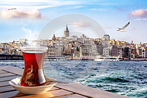 A cup of Turkish tea in a traditional glass against the background of the Golden Horn and the Galata Tower in Istanbul