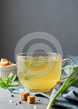 A cup of warming home broth on a concrete background