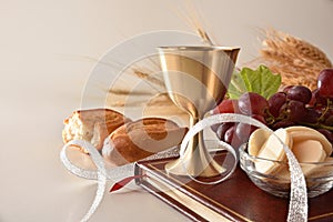 Cup of wine and hosts on bible for eucharist isolated white photo
