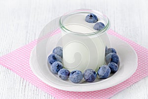 A cup of yogurt with blueberrys on the table