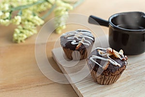 Cupcake Almond. Chocolate cake sprinkled with almonds served with hot coffee. Delicious cake. Cake with icing sugar on wood table