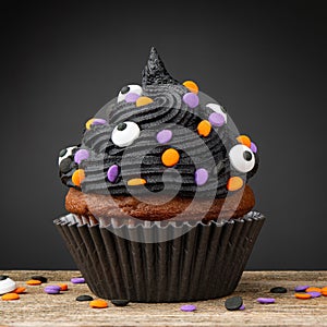 Cupcake. Black cupcake on Halloween. Dessert on Halloween party. Chocolate muffin decorated with colored sprinkles