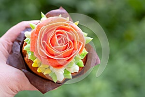 Cupcake decorated with cream rose in the hand, flowers of Korean butter