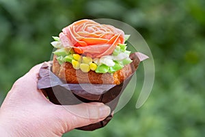 Cupcake decorated with cream rose in the hand, flowers of Korean butter