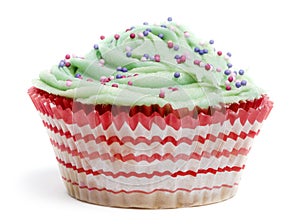 Cupcake with green icing and hundreds and thousands against white background