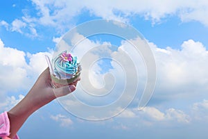 Cupcake in hand on blue sky background