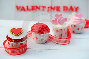 Cupcake with heart decoration on a white wooden background. Love and Valentine`s day concept