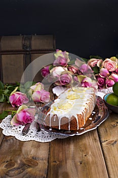 Cupcake with lime and white cream on an old tray, pink roses and a wooden background