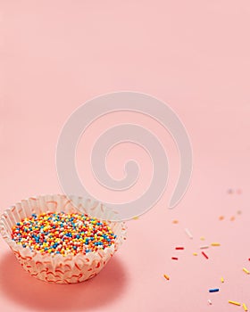 Cupcake liners with colored sugar inside and near it. Confectionery cooking concept with copy space on pink bright paper
