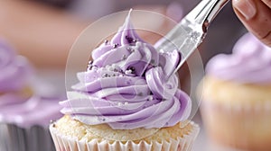 A cupcake receives a coating of vivid purple frosting, enhancing its sweetness and visual appeal