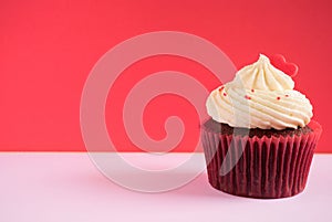 Cupcake with red heart over red background