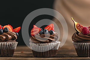 Cupcake with strawberries, raspberries, blueberries, figs. Chocolate muffins decorated with seasonal fruits and berries
