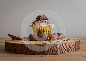 Cupcake with vanilla frosting and chocolate on a wooden platform