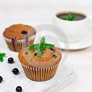 Cupcakes with black currant and mint leaves on a white plate. Close-up. Selective focus.