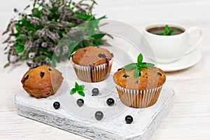 Cupcakes with black currant and mint leaves on a white plate. Selective focus.