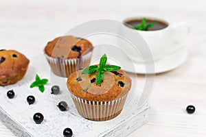 Cupcakes with black currant and mint leaves on a white plate. Selective focus.