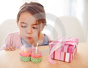 Cupcakes, blowing candles and girl with birthday, kid and gift with happiness, candy and home. Childhood, celebration