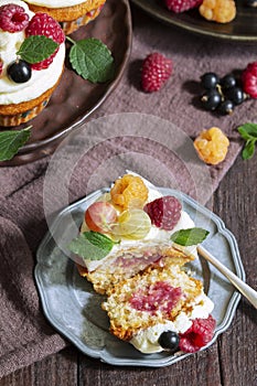 Cupcakes with butter cream and raspberry curd, decorated with berries on a wooden surface.