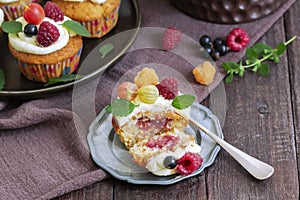 Cupcakes with butter cream and raspberry curd, decorated with berries on a wooden surface.