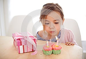 Cupcakes, candles and girl with birthday, gift and celebration with happiness, candy and home. Childhood, kid or excited