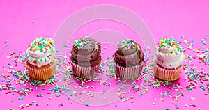 Cupcakes with colorful sprinkles on pink background