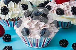 CUPCAKES WITH CREAM AND BERRIES.