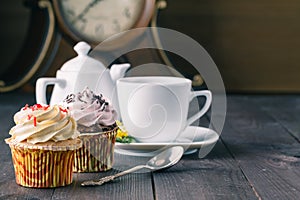 Cupcakes and cup of tra on dark wooden background