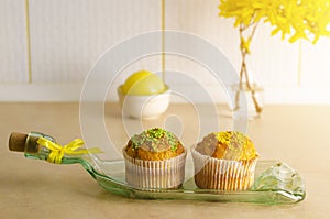 Cupcakes decorated with sprinkles on a plate made from bottle on a kithchen table. Breakfast and dessert concept.