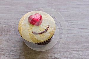 A cupcakes with heart shape chocolate on wooden table