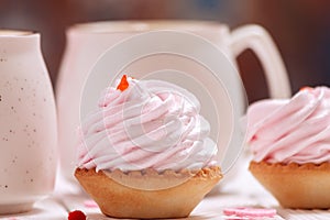 Cupcakes with pink cream and coffee mugs close-up. The concept of Valentine`s Day or Birthday, wedding day