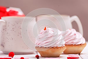 Cupcakes with pink cream and coffee mugs close-up. The concept of Valentine`s Day or Birthday, wedding day