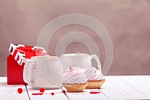 Cupcakes with pink cream and coffee mugs close-up. The concept of Valentine`s Day or Birthday, wedding day
