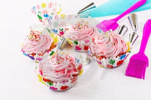 Cupcakes with pink whipped cream swirl and confectionery syringe