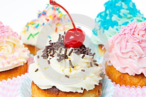 Cupcakes with whipped cream decorated sprinkles and maraschino cherry
