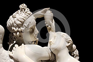 Cupid and Psyche white marble statue isolated on black background photo