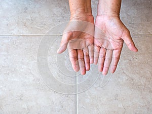 Cupped hands of old woman on tile background