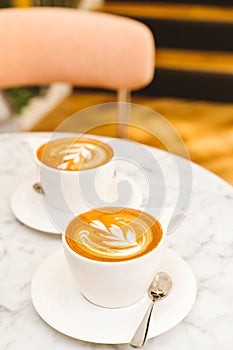 Cups of cappuccino on the white marble table in a modern cafe