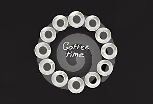 Cups with coffee, stacked in a circle. Clock consist of twenty cups. Black background. Concept time to coffee