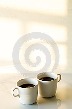 Cups of coffees on white marble table in morning light