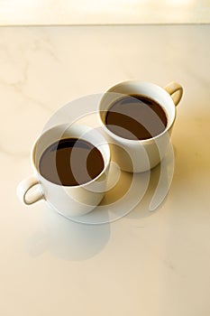 Cups of coffees on white marble table in morning light