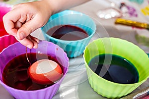 Cups of dye with an egg being lowered in for Easter decorations