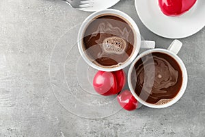 Cups of hot chocolate with red hearts on grey table