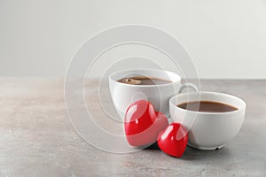 Cups of hot chocolate with red hearts on grey table