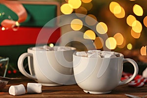 Cups of hot cocoa with marshmallows on table against blurred background