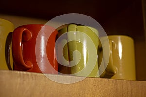 Cups on shelf. Colorful glasses for drinks. Utensils in kitchen. Containers for liquids. Interior details