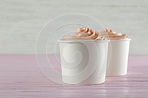 Cups with tasty frozen yogurt on wooden table. Space for text