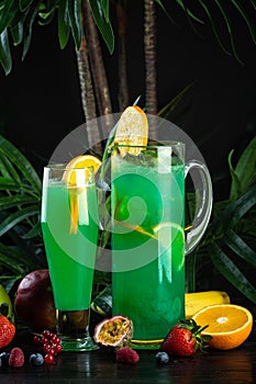 Curacao lemonade in a glass and jug decorated with an orange slice