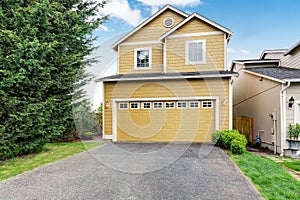 Curb appeal. Yellow two level house exterior with garage.